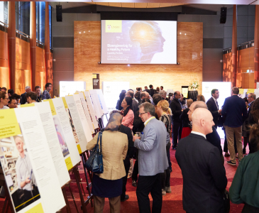 A crowd of people in a large room looking at information on cardboard posters