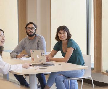 Three people sitting at a table looking to the right