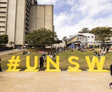 View towards UNSW library of lawn with a sign that says #UNSW