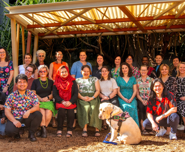 A large group of course attendees posed beneath a wooden shelter at Charles Darwin University 