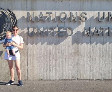 Woman holds child before United Nations building