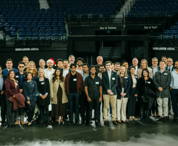 A group shot of many alumni in an arena.