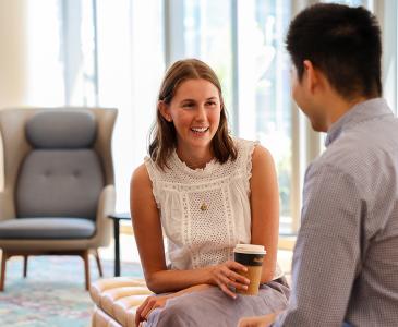 A seated woman smiling and talking to a man 