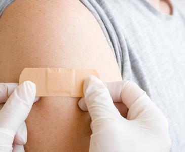 Someone getting a plaster on their arm, following a vaccine