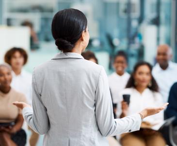 Woman giving presentation to group of staff