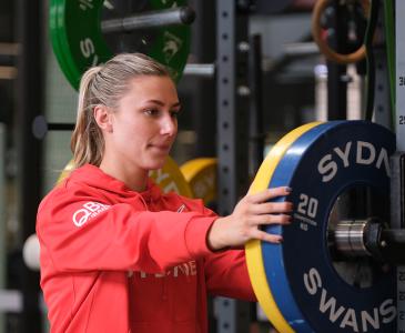 A woman in a red jacket holding her hands on weight disks