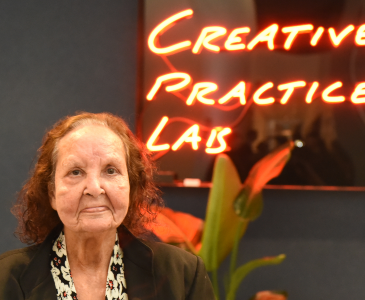 Artist Esme Timbery in front of neon sign 