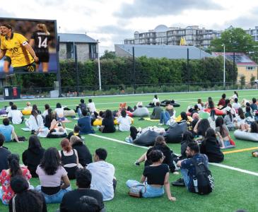 Crowd of people watching sport on an outdoor screen