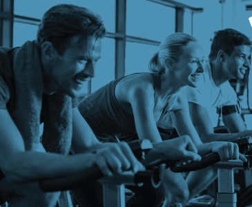 Three people on exercise bikes in black and blue with Fitness Passport logo in top right