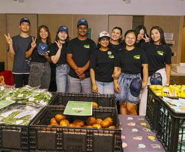 A group of people standing behind boxes of produce