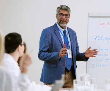 A man standing at a white board in front of a group of people