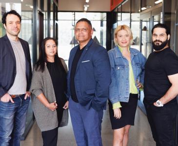 Five Aboriginal Australians stand in front of a modern office building