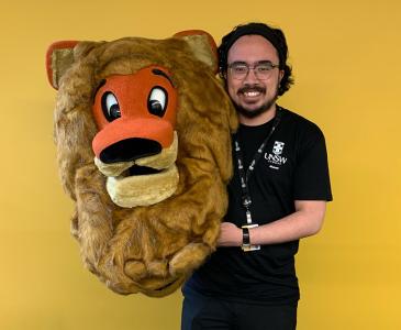 A young man holds a lion's head costume