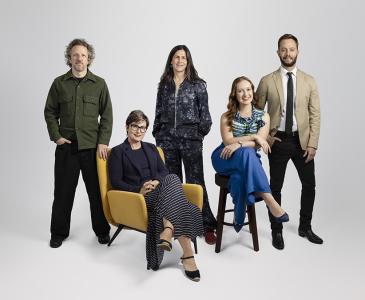 A group of people posed against a grey background