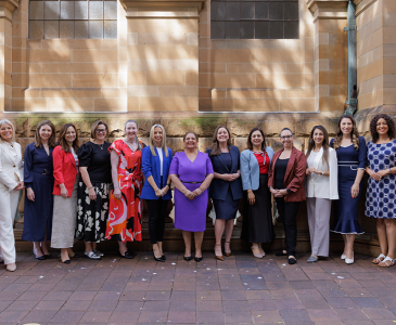 A group of women standing in front of a sandstone building.