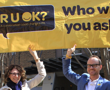 Two people holding up an R U Ok? banner