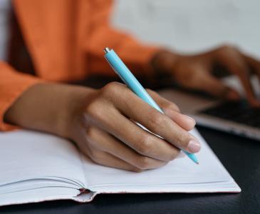 Close-up of a woman's hand holding a pen and writing