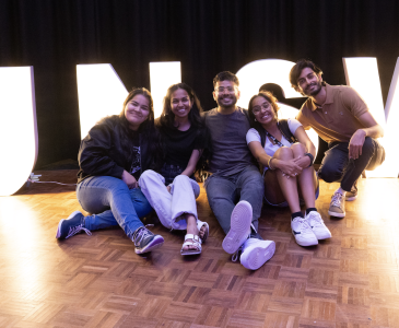 students sitting in front of an illuminated UNSW sign