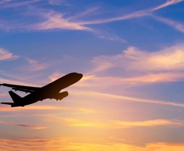 A plane flying through a sunset sky.
