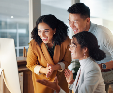 Three people smiling at a computer.
