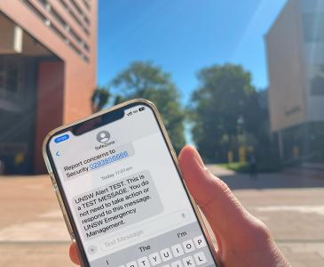 Close up of a hand holding a phone with a text alert