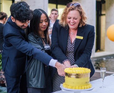 CEO Sarah Lightfoot cutting cake with students 