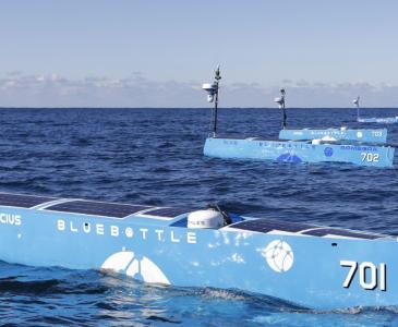 Three blue unmanned robot boats on the open ocean