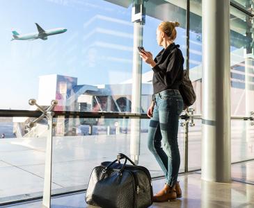 A woman watching an airplane take off from inside the airport