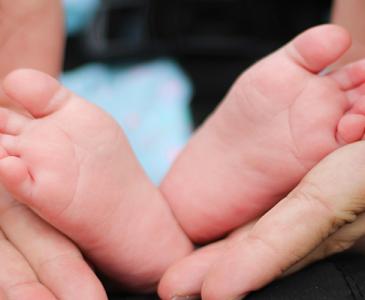 A parent holding their baby's feet