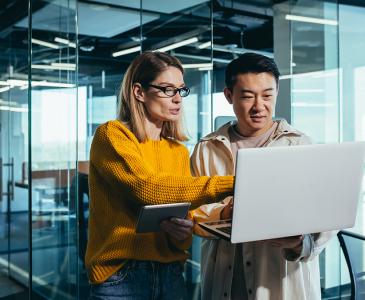 Two people standing and pointing to a laptop screen