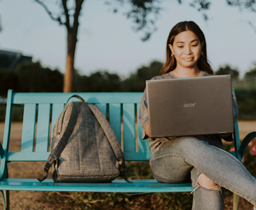 Student using a laptop on park bench