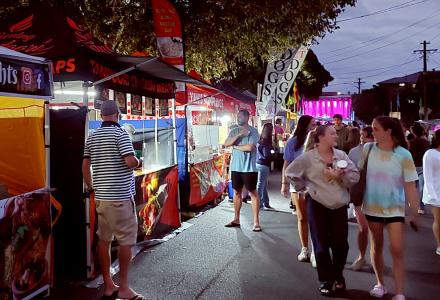 People walking through a night market with food stalls