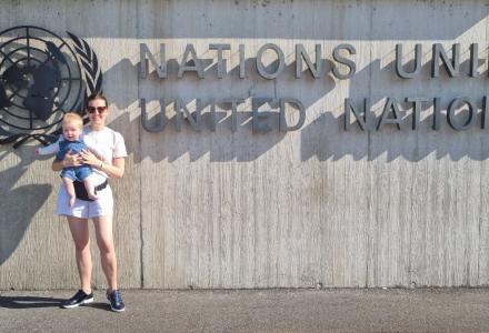 Woman holds child before United Nations building