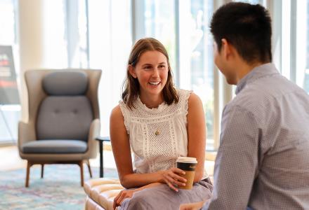 A seated woman smiling and talking to a man 