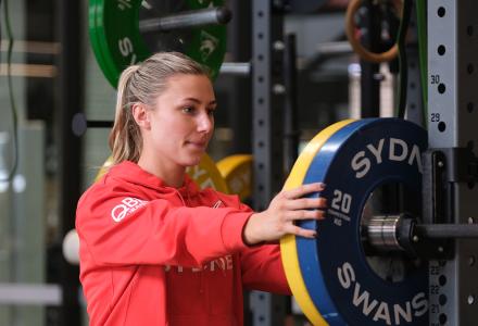 A woman in a red jacket holding her hands on weight disks