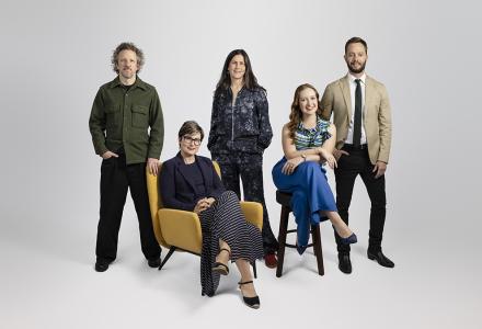 A group of people posed against a grey background