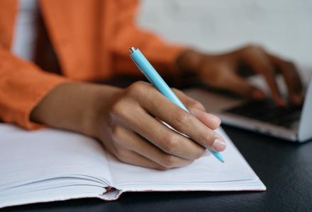 Close-up of a woman's hand holding a pen and writing