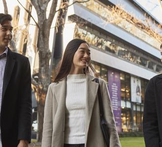 Three students wearing winter clothing walking on lower campus
