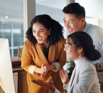 Three people smiling at a computer.