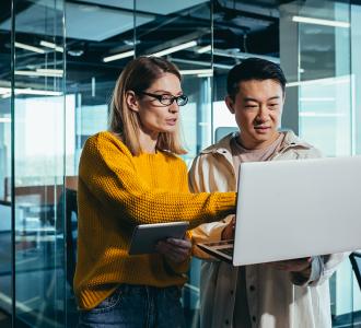 Two people standing and pointing to a laptop screen