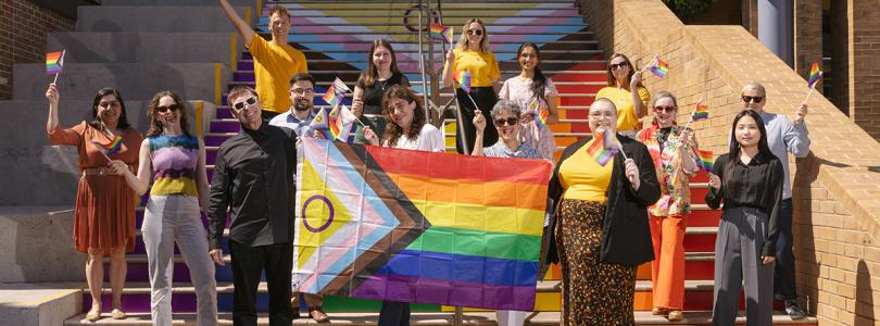 UNSW staff gathered at the Basser Steps with rainbow flags