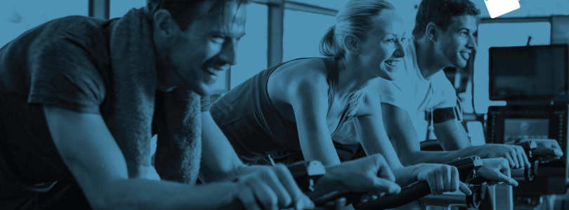 Three people on exercise bikes in black and blue with Fitness Passport logo in top right